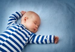 sleeping baby in stripes for article on sleep by Dr Anne Malatt