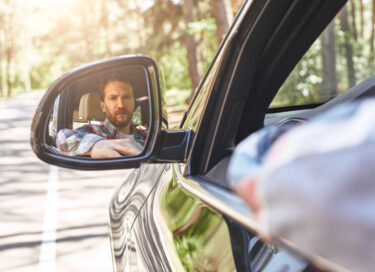 Man looking in blind spot mirror for article on blind spots by Dr Anne Malatt